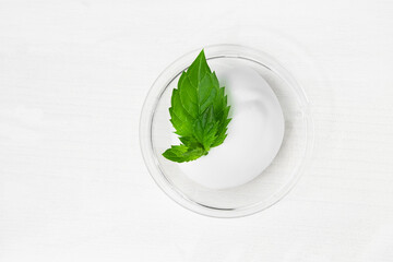 A smear of cosmetic white cream on a white wooden table with green mint leaves. Body lotion, body...