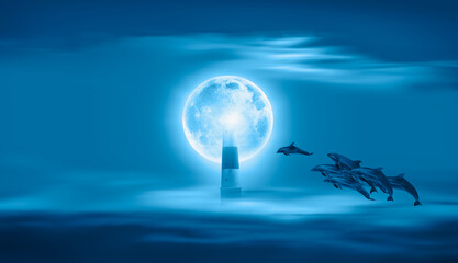 Group of dolphins jumping on the water - Night sky with lighthouse, in the background amazing blue moon in the clouds  "Elements of this image furnished by NASA