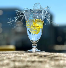 glass of water  and  drops splas with lemon  on beach at sunset nature landscape