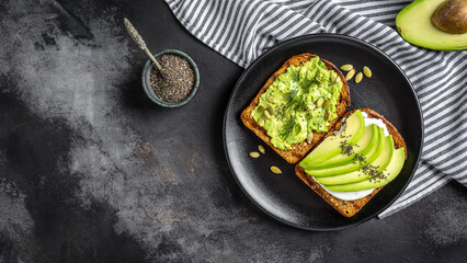 Healthy avocado toasts for breakfast or lunch with rye bread, sliced avocado, arugula, pumpkin and sesame seeds, salt and pepper. Vegetarian sandwiches. Plant-based diet. Whole food concept