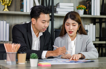 Asian young professional businesswoman secretary sitting smiling working showing graph chart paperwork document report to successful businessman entrepreneur in formal suit drinking coffee from cup