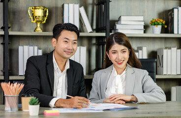 Asian young professional businesswoman secretary sitting smiling working showing graph chart paperwork document report to successful businessman entrepreneur in formal suit drinking coffee from cup