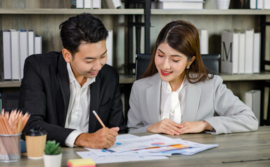 Asian young professional businesswoman secretary sitting smiling working showing graph chart paperwork document report to successful businessman entrepreneur in formal suit drinking coffee from cup
