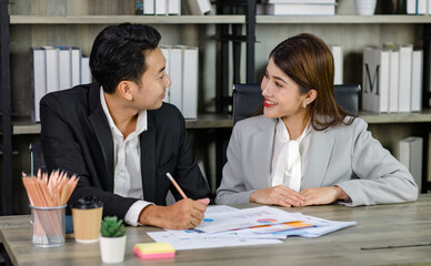 Asian young professional businesswoman secretary sitting smiling working showing graph chart paperwork document report to successful businessman entrepreneur in formal suit drinking coffee from cup