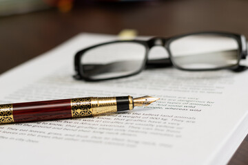 a workplace with documents, glasses and a signature pen for a businessman's day. Nobody.