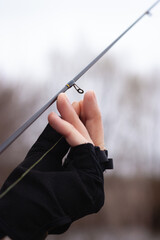 A closeup of a hand of a man putting a thread into the fishing rod