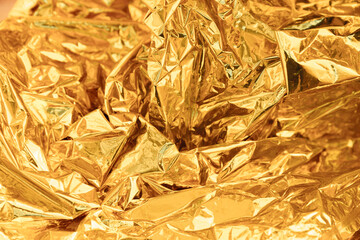 Golden wrinkled foil texture. Shiny yellow background