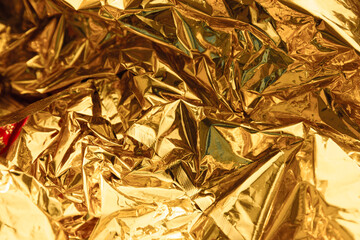 Golden wrinkled foil texture. Shiny yellow background