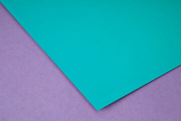 Plain blue green paper sheet lying on pink purple textured Background like an open book from top angle	