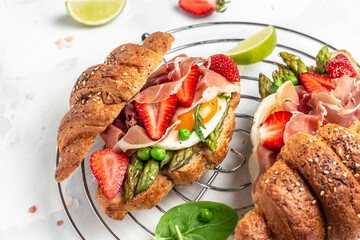 Delicious fresh breakfast served grilled bun with spinach and cheese, asparagus, jamon, ham, prosciutto and fried egg. fresh juice, Balanced diet. place for text, top view