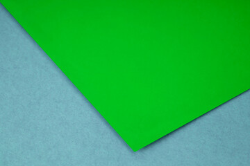 Plain lime green paper sheet lying on blue grey textured Background like an open book from top angle