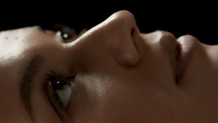 Big close-up shot of young good-looking African American female model's face on black background | Eyes care concept