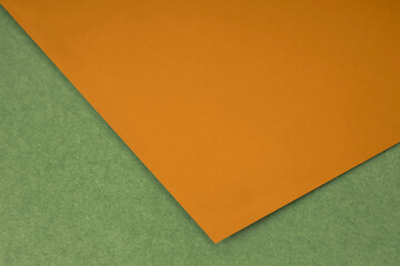 Plain orange paper sheet lying on yellow green textured Background like an open book from top angle	