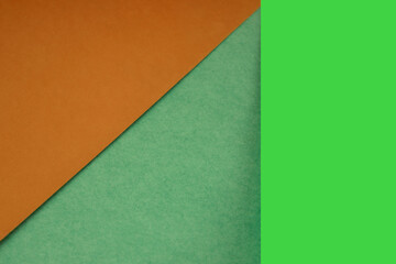 Fototapeta premium Textured and plain orange green sheet papers forming two triangles and vertical blank rectangle for creative cover designing
