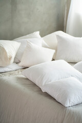 Photo of comfortable soft pillows on the bed. Closeup light bedding sheets. Designer bedroom interior.