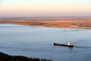 Aerial photography of cargo ships sail on the Danube river at sunset.