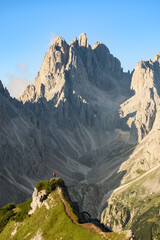 Stunning view of a tourist on the top of a hill enjoying the view of the Cadini di Misurina during sunrise. Cadini di Misurina is a group of mountains located in the Dolomites, Italy.