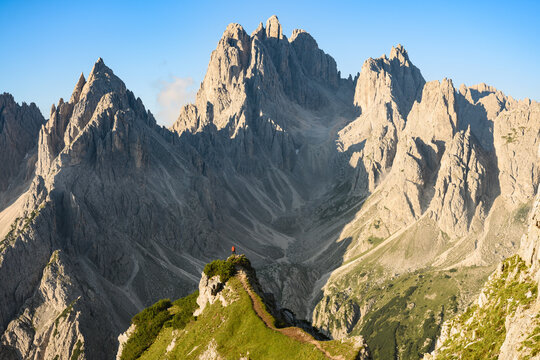 Stunning view of a tourist on the top of a hill enjoying the view of the Cadini di Misurina during sunrise. Cadini di Misurina is a group of mountains located in the Dolomites, Italy.