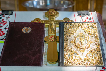 Two Bibles and a large golden cross on an altar in a Christian church