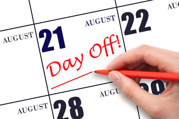 Hand writing text DAY OFF and drawing a line on calendar date 21 August. Vacation planning concept.