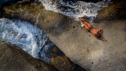 Woman in bikini relaxes on a rock in a Mediterranean island - 518284985