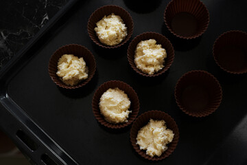 woman housewife preparing muffins in silicone molds in her kitchen close-up