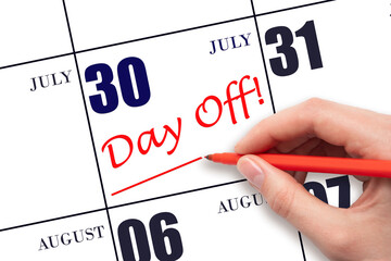 Hand writing text DAY OFF and drawing a line on calendar date 30 July. Vacation planning concept.
