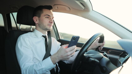 Concentrated man sitting at driver's seat in car and chatting. Businessman in Automobile. Concept, innovation, message, communication, holding, messaging