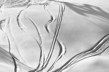 Black and white off-piste slope with track from ski and snowboard on sunny evening
