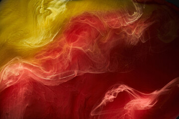 Liquid fluid art abstract background. Red, yellow dancing acrylic paints underwater, space smoke ocean, color explosion