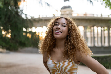 pretty hispanic woman with curly hair smiling traveler in the city