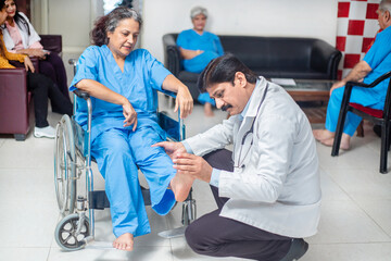 Indian doctor check disabled elder woman patient sit on wheelchair at home hospital, paralyzed old...