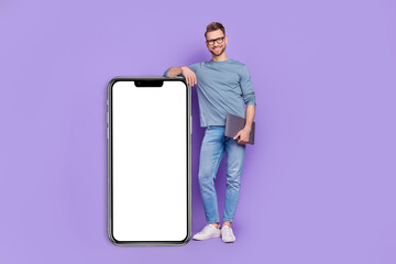 Photo of pretty attractive guy dressed grey shirt holding modern gadget empty space isolated purple color background