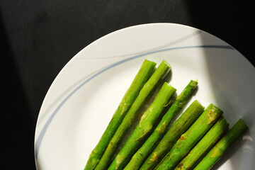 fried asparagus on a white plate on the table close-up top view
