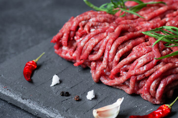 Raw minced meat on stone board with thyme, black peppers and garlic, butcher concept