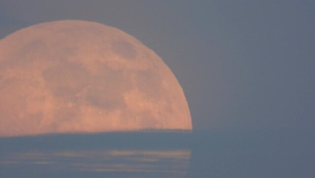 orange supermoon rising behind clouds. Static still shot