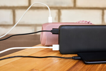 Powerbank charges smartphone and portable speaker using usb. Close-up, selective focus