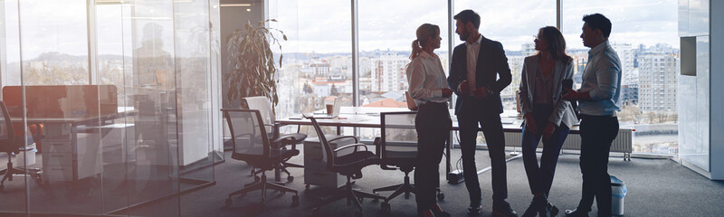 Business team standing against panoramic windows in modern office. High quality photo