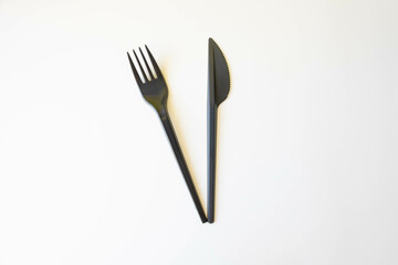 Top view of black plastic disposable fork and knife isolated on white