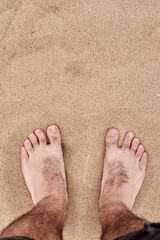 Men's feet stand on beautiful yellow coarse sand. Sharp sand. A man walks on tropical sand.