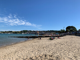 Fototapeta na wymiar Beach at Swanage Dorset England UK. Crowded sandy beach with wind breaks and view of town in the rear. Deck chairs and sandcastles. A traditional summer holiday scene.