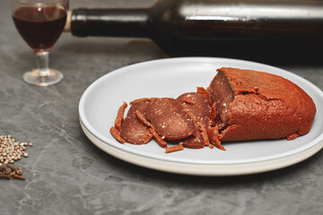 sliced basturma on a plate next to a bottle of wine and a glass