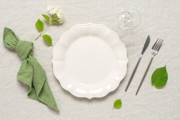 Modern minimal table place setting beige and green color. Top view, flat lay. Selective focus.