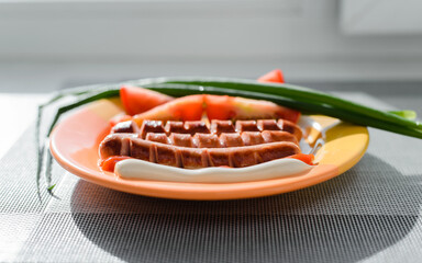 Grilled sausages, tomatoes, green onions with ketchup and mayonnaise on a plate inside. Close-up, selective focus