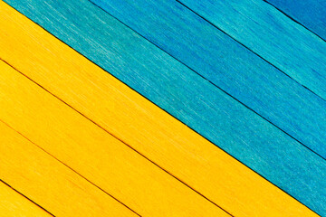 Bicolor wooden textured background in blue and yellow colours. Wooden boards are painted  and arranged diagonally. Blue and yellow separated wooden background.