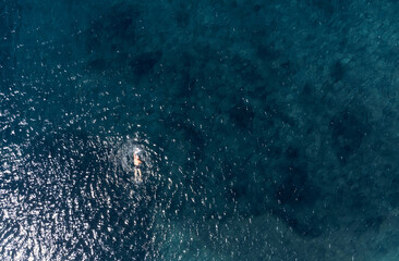 Aerial top view of a senior man swimming in the sea.