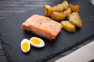 baked salmon fillet with fried potato wedges and quail eggs halves