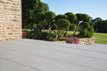 Keuken spatwand met foto Modern garden design and landscaping:Hillside plot paved with natural sidewalk flagstones in contrast to a raised bed with natural stone walls, planted with succulents, flowers and beautiful boxtrees © blickwinkel2511