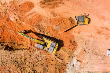 Construction site preparation work with an excavator loading earth into dump trucks