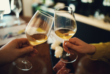Man and a woman clink glasses of white wine.